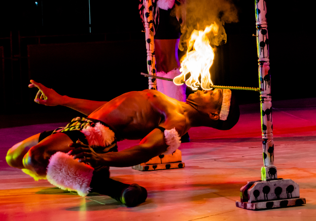 Eine Person schaut auf ein Feuer, das auf einer Stange befestigt ist, die an Pfählen angebracht ist.