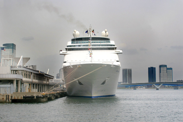 Ein Schiff schwimmt auf dem Wasser neben einer Brücke und zahlreichen Gebäuden.