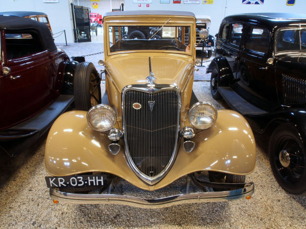 Eine Gruppe von Oldtimern in einem Museum ausgestellt, mit Plakaten an der Hintergrundwand.