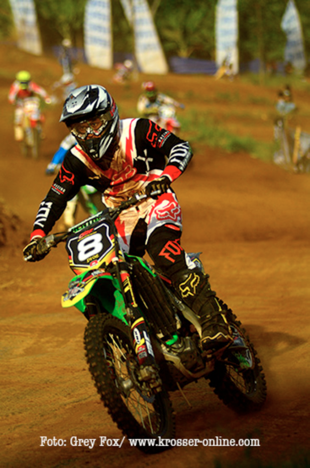 Mehrere Personen auf Motorrädern bei einem Rennen, alle tragen Helme, mit Text am unteren Bildrand.