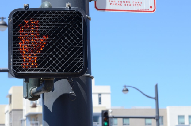 Eine Straßenszene in einer Stadt mit Verkehrspfählen, Ampeln, Straßenlaternen, Gebäuden und Himmel.