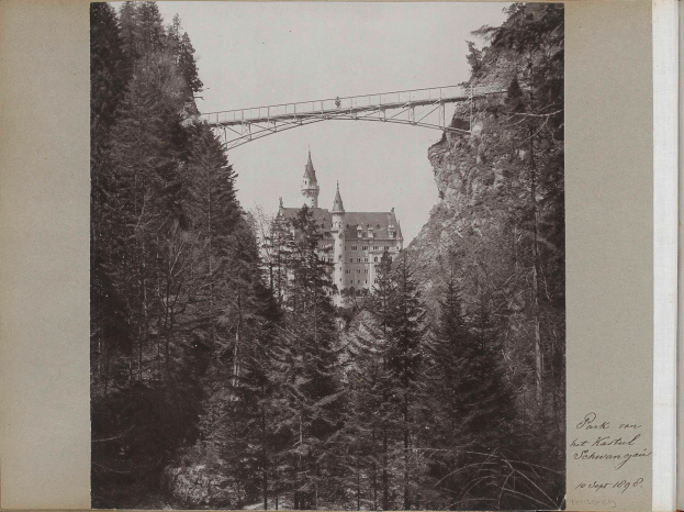 Ein Schwarz-Weiß-Foto der Neuschwanstein Burg in Deutschland, mit einer Brücke im Vordergrund, Bäumen drumherum und Text auf der rechten Seite.