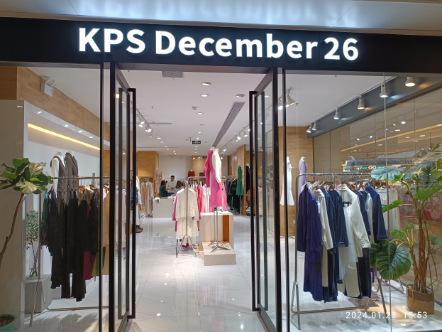 Das Innere eines KPS-Geschäfts am 26. Dezember in Singapur, mit Kleidung an Bügeln, bekleideten Schaufensterpuppen, Topfpflanzen, Glaswänden, Deckenlampen und einem Schild mit Text, wobei der Boden unten zu sehen ist.