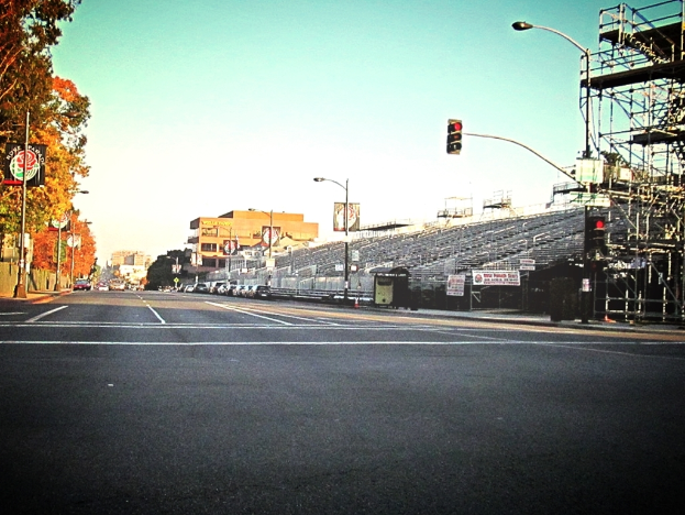 Eine Stra√üe mit einem Verkehrszeichenmast und Ger√§t auf der rechten Seite, Warnschilder und mehrere Fahrzeuge auf der linken Seite und B√§ume im Hintergrund.