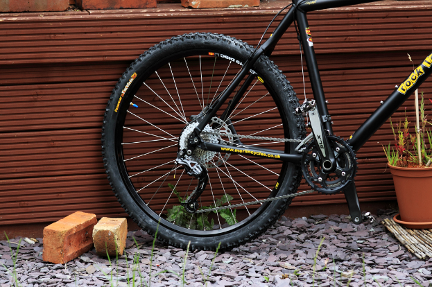 Eine Szene mit Ziegelsteinen, Felsen, Pflanzen, einer Wand und einem Fahrrad.