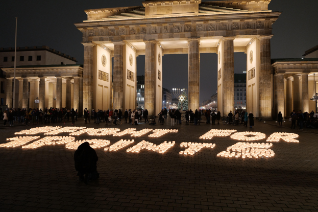 Eine Gruppe von Menschen steht vor dem beleuchteten Reichstag in Berlin, Deutschland, umgeben von Gebäuden, Masten und Lichtern; die Worte "Kampf für Freiheit" sind im Vordergrund zu sehen.