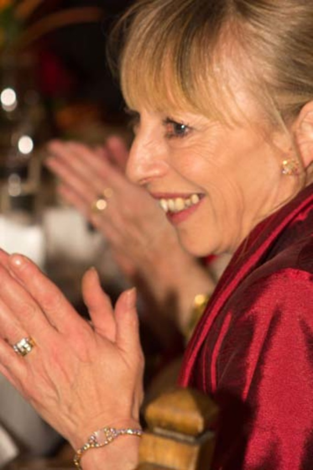 Eine Frau klatscht mit einer sichtbaren menschlichen Hand dahinter.