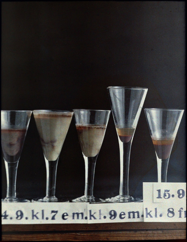 Five martini glasses in a row on a table, each labeled with a number and containing a different drink.