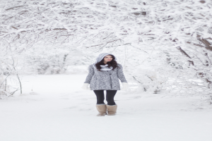 Eine Frau steht im Schnee mit ein paar schneebedeckten Bäumen im Hintergrund.