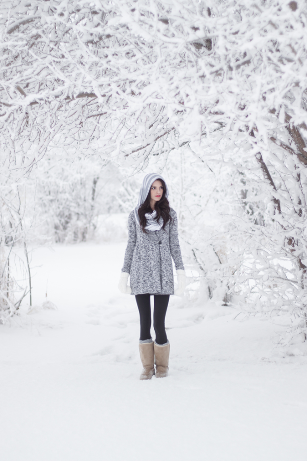Eine Frau steht im Schnee mit ein paar schneebedeckten Bäumen im Hintergrund.