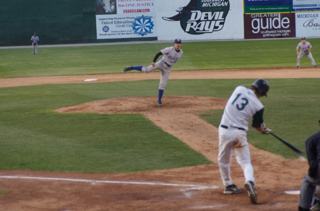 Eine Gruppe von Menschen spielt Baseball auf einem Feld mit Bannern im Hintergrund.