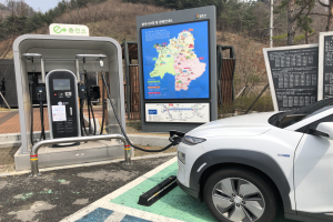 Ein Elektroauto lädt an einer Station in Seoul, Südkorea, umgeben von Bäumen mit dem Himmel im Hintergrund.