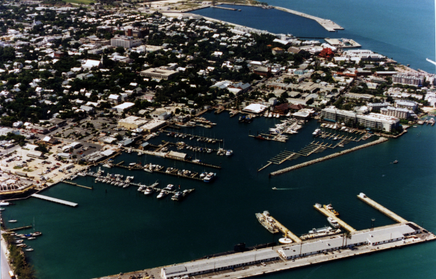 Eine Vogelperspektive einer Stadt mit zahlreichen Gebäuden, Meerwasser und einem Hafen an der unteren Vorderseite, mit mehreren Schiffen.