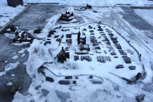 Eine Stadtkarte ist auf einem schneebedeckten Boden zu sehen, umgeben von Gebäuden und anderen Gegenständen, mit schneebedecktem Boden, der sich in den Hintergrund erstreckt.