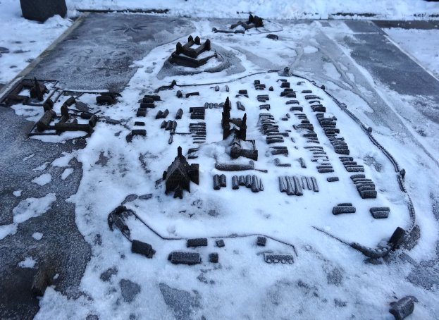 Eine Stadtkarte ist auf einem schneebedeckten Boden zu sehen, umgeben von Gebäuden und anderen Gegenständen, mit schneebedecktem Boden, der sich in den Hintergrund erstreckt.