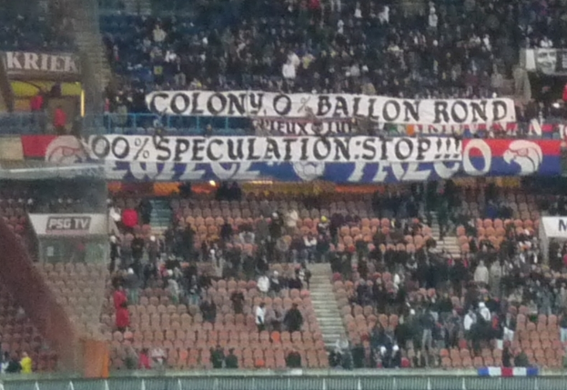 Ein Stadion mit einer gro√üen Menge, Bannern und St√ľhlen, mit einem Zaun unten und Treppen auf der linken Seite.