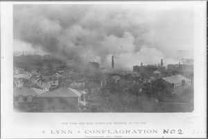 Ein Schwarz-Weiß-Foto einer Stadt mit Rauch, der aus den Gebäuden, Bäumen und dem Himmel aufsteigt, mit dem Text "Lynn und Conflagration No. 2" unten.