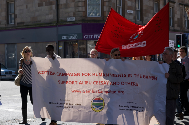 Ein Gebäude mit Bannern, eine Ampel und einige verstreute Menschen.