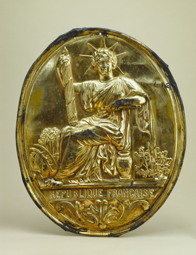 Goldenes rundes Schild mit einer Statue der Freiheitsstatue und eingraviertem Text auf weißem Hintergrund.