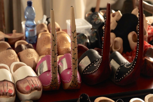 Ein Tisch mit mehreren Schuhen, einer Flasche, einem Becher und einer Schachtel.