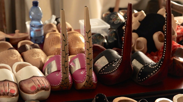 Ein Tisch mit mehreren Schuhen, einer Flasche, einem Becher und einer Schachtel.