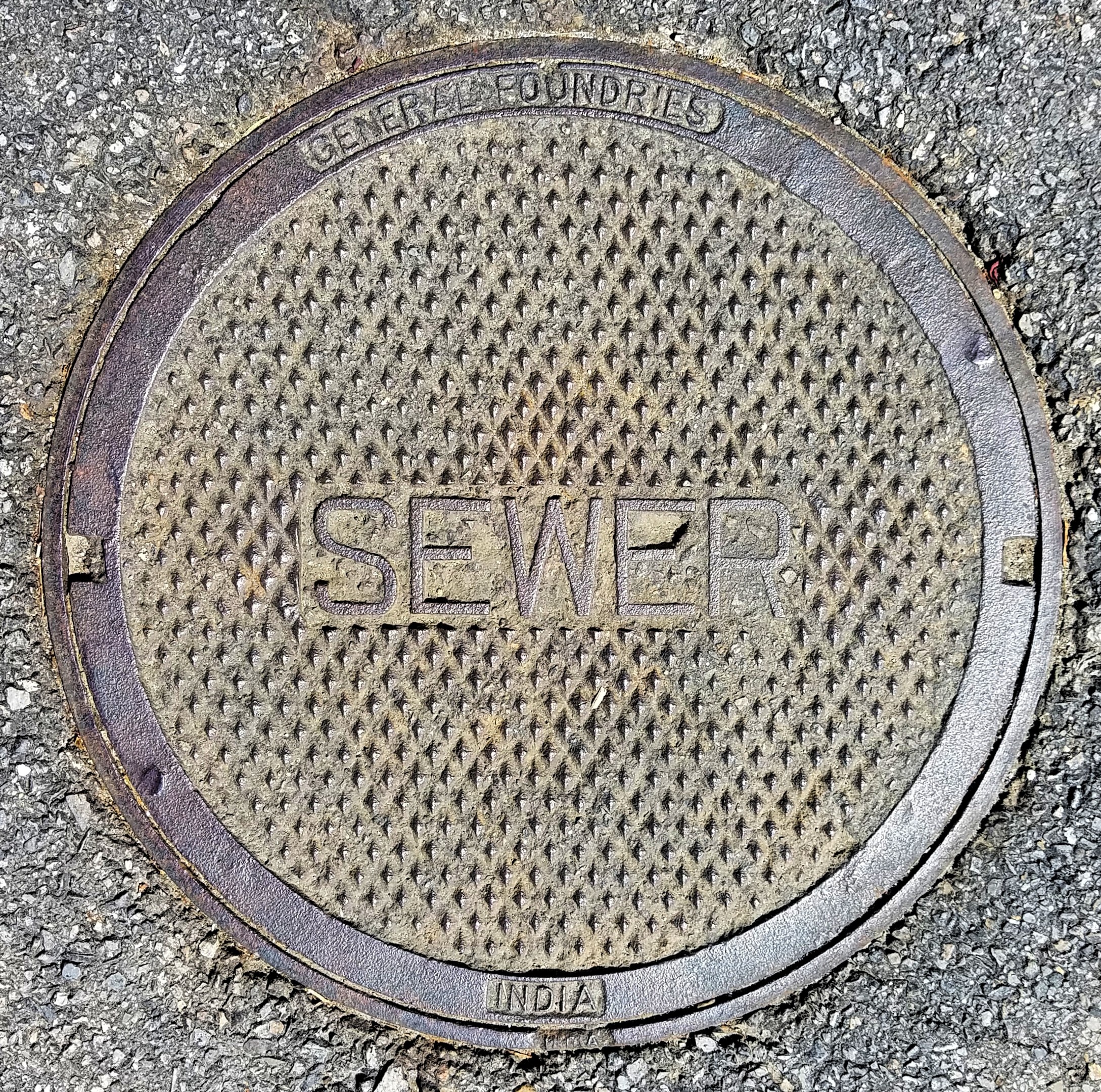 Metallschachtdeckel auf der Straße mit der Aufschrift "Kanal"