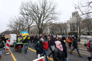 Eine große Gruppe von Menschen marschiert auf einer Straße in Washington, D.C. am 21. Januar 2020, einige halten Schilder und Banner, andere fahren Fahrräder, mit Schildern, Bäumen und einem klaren blauen Himmel im Hintergrund.