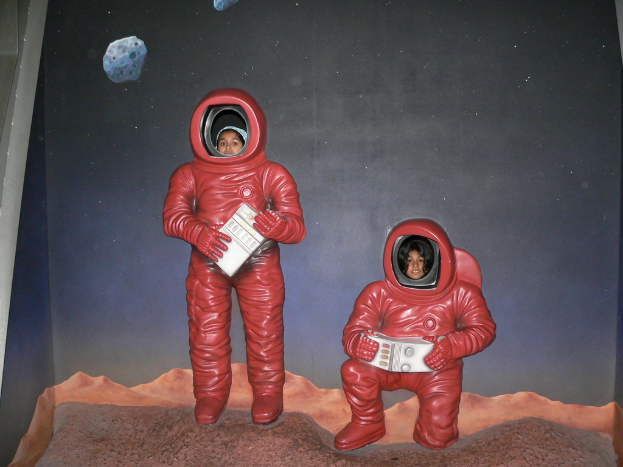 Ein Plakat mit Astronauten, auf deren GesÃ¤rzen Kinder Gesichter Ã¼berlagert sind.