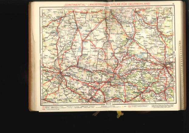 Ein aufgeschlagenes Buch mit einer detaillierten Deutschlandkarte mit Straßen und Autobahnen auf schwarzem Hintergrund.