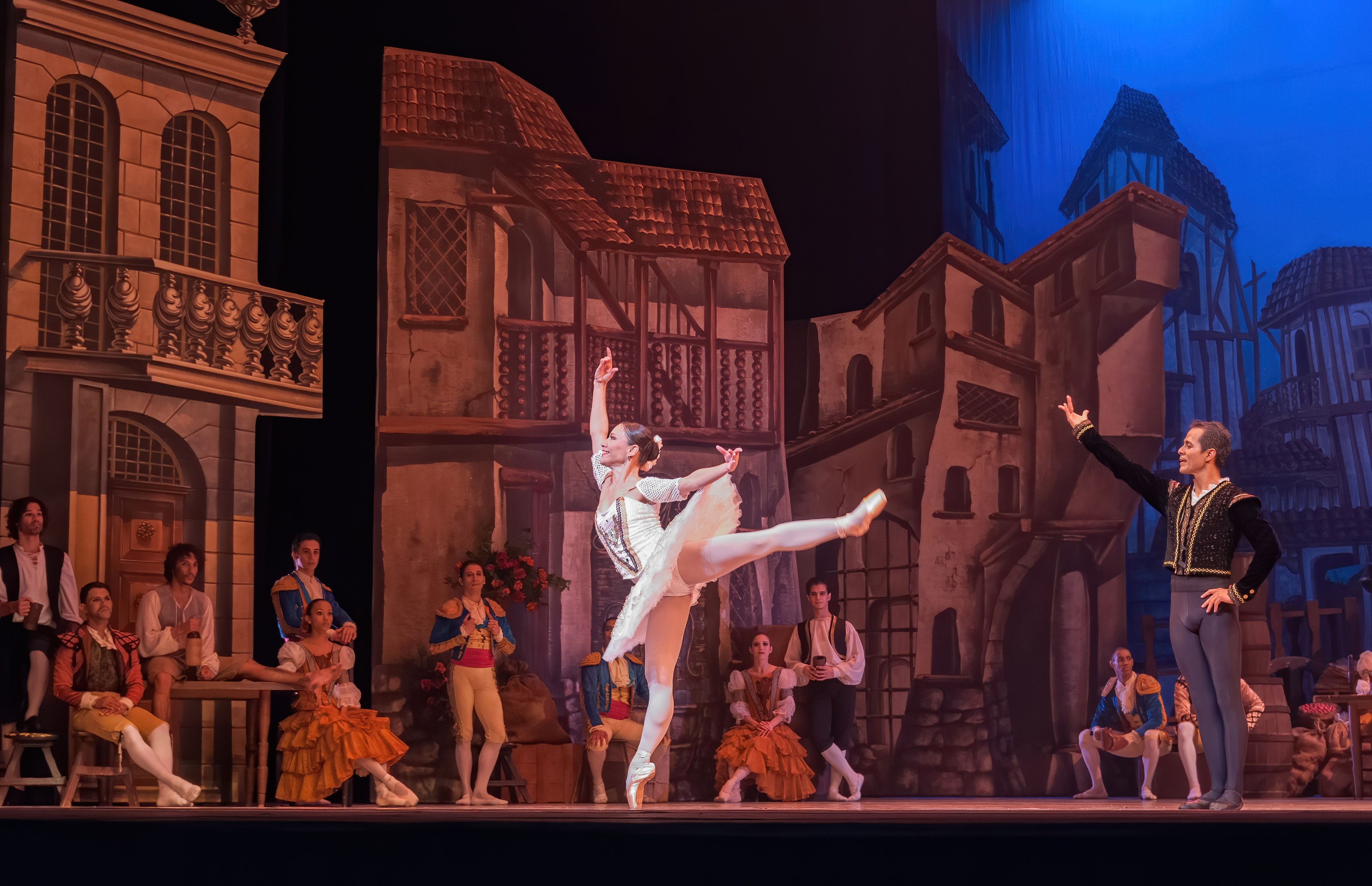 Zwei Tänzer performen auf einer Bühne in der Royal Opera House in London, mit einem Publikum im Vordergrund und einem Bildschirm mit Gebäudeabbildungen im Hintergrund.