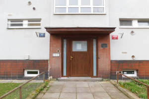 Zweizimmer-Reiheneckhaus mit weißer Fassade, brauner Tür und Fenstern, Metallzaun, Gras, Weg und Brettern an der Wand, gelegen in St Johns Court, St Johns Road, Luton.