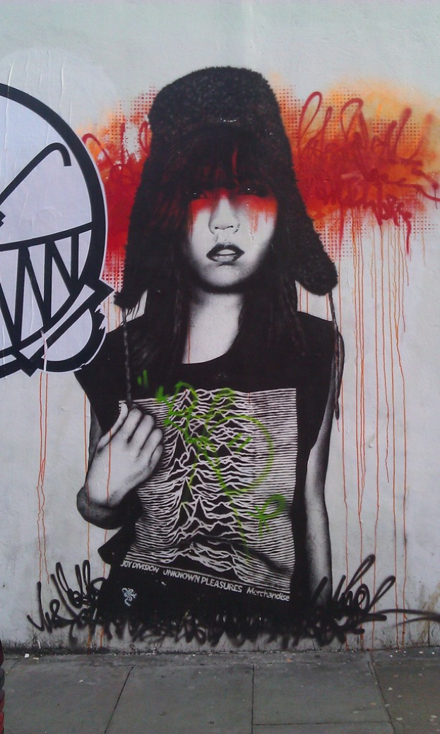 Graffiti an einer weißen Wand mit Gehweg unten.