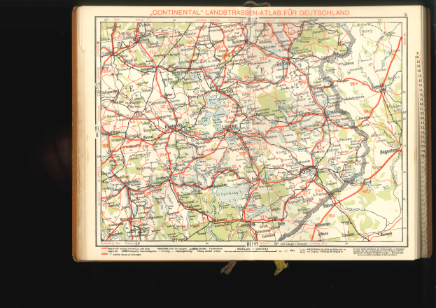 Ein altes Buch mit einer detaillierten Deutschlandkarte auf dem Cover, das Straßen und Autobahnen zeigt, vor schwarzem Hintergrund.