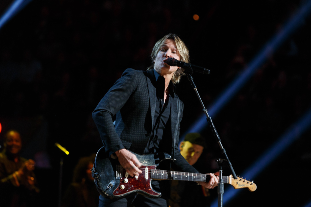 Keith Urban performs auf der Bühne im Joint in Las Vegas, spielt eine Gitarre mit einem Mikrofon davor und Musiker im Hintergrund, unter dunkler Beleuchtung.