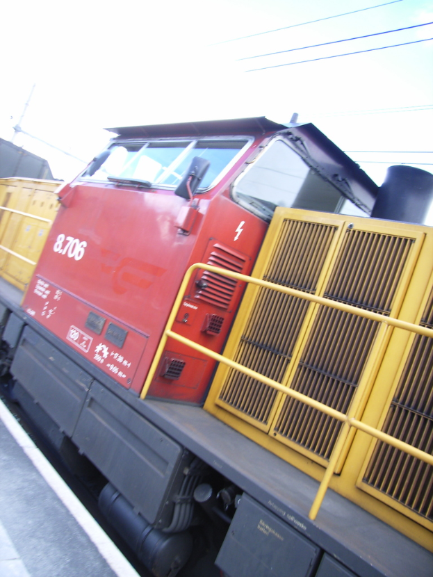 Ein Zug auf den Schienen mit Kabeln und dem Himmel im Hintergrund.