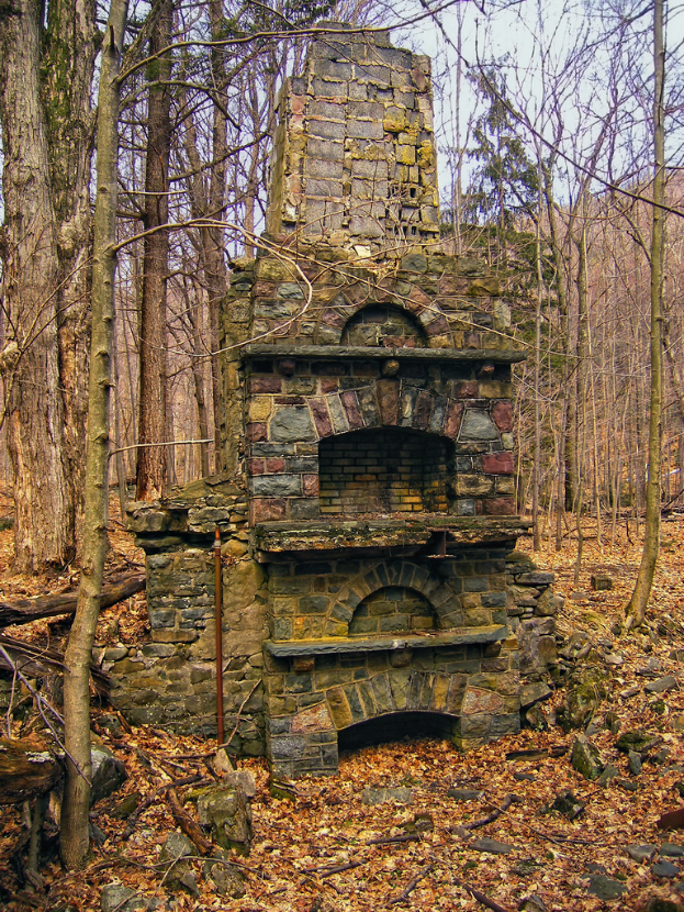 Ein Ziegelgebäude mit Bäumen im Hintergrund und Steinen am Boden.