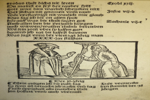 Ein Blatt Papier mit gedrucktem Text in einer fremden Sprache, mit zwei Männern im Hintergrund, möglicherweise aus einem Schulbuch.