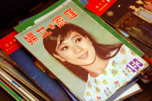 Eine Sammlung von Zeitschriften auf einem Tisch mit der oberen Zeitschrift, die ein Bild einer Frau zeigt.