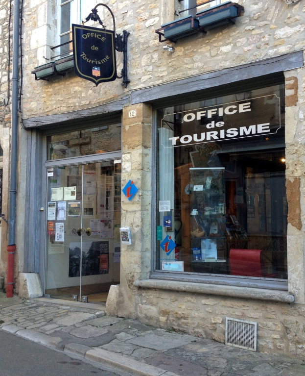 Tourismus-Büro-Gebäude mit einem "Office de Tourisme"-Schild, Fenstern, einer Tür mit Papieren, einem Rohr an der Seite und einer Straße unten.