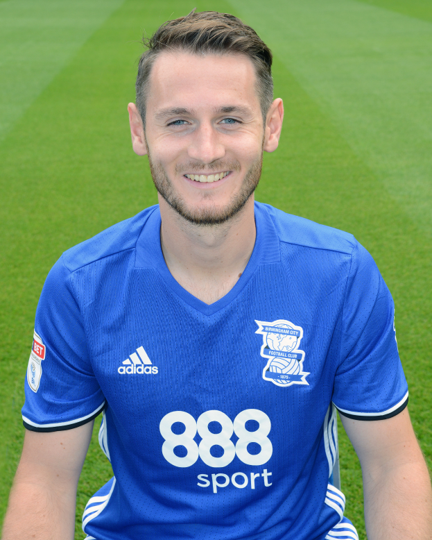 Ein Mann sitzt auf einem Fussballfeld, trägt ein blaues T-Shirt und lächelt, mit Text unten, der eine Trainingseinheit anzeigt.