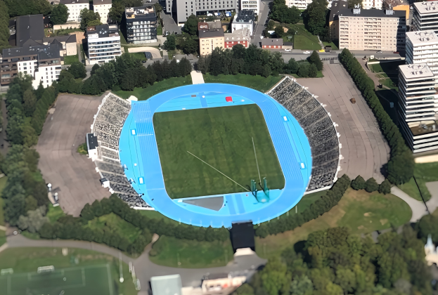 Luftaufnahme des Olympiastadions in München, Deutschland, umgeben von städtischen Gebäuden, Bäumen, Straßen, Fahrzeugen und Gras.