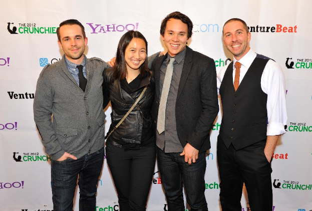 Eine Gruppe strahlender Menschen, die vor einer Sponsoren-Wand posieren.