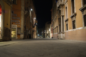 Eine Nachtansicht einer Straße mit Gebäuden auf beiden Seiten, einem Geschäft auf der linken Seite und Lichtern in der Mitte.