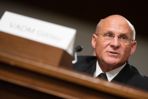 Ein Mann in Anzug und Krawatte sitzt an einem Tisch mit Namensschild und Mikrofon und spricht vor dem Senatsjustizausschuss auf dem Capitol Hill in Washington, D.C., mit einem unscharfen Hintergrund.