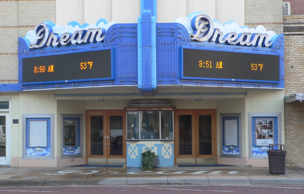 Außenansicht des Dream Theaters in St. Louis, Missouri, mit Glastüren und -fenstern, einer Schautafel, einem Müllbehälter, einem Topf mit einer Pflanze und einer Straße im Vordergrund.