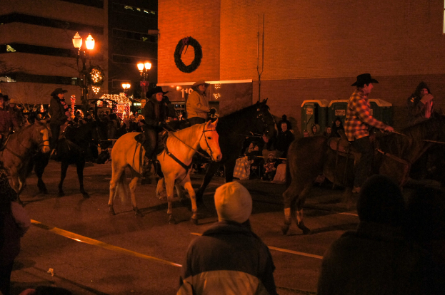 Eine Gruppe von Menschen reitet auf Pferden eine Straße entlang.