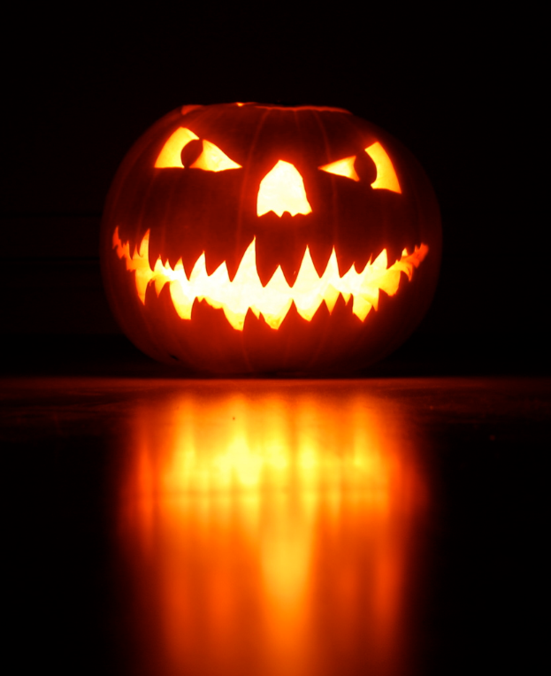 Eine geschnitzte Pumpkin steht auf dem Boden mit einem dunklen Hintergrund.