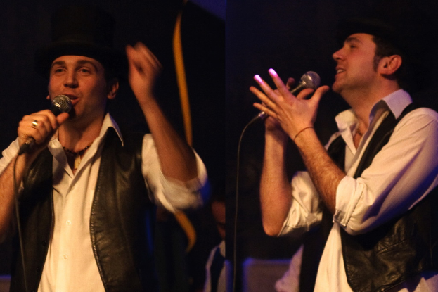 Eine Gruppe von Menschen mit zwei Personen vorn, die in Mikrofone singen.