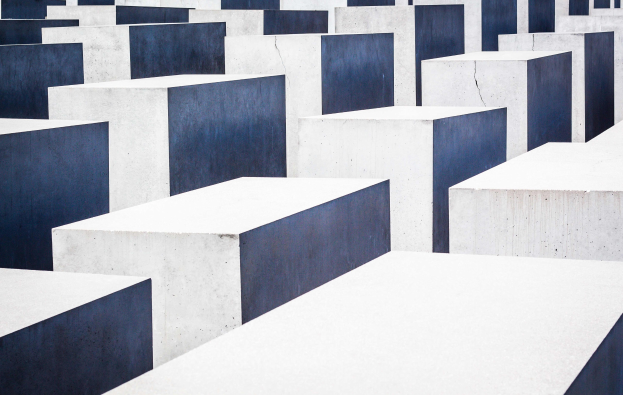 Luftaufnahme des Holocaust-Mahnmals für die ermordeten Juden Europas in Berlin, das zahlreiche weiße und blaue Betonsteine in einem Gittermuster zeigt.