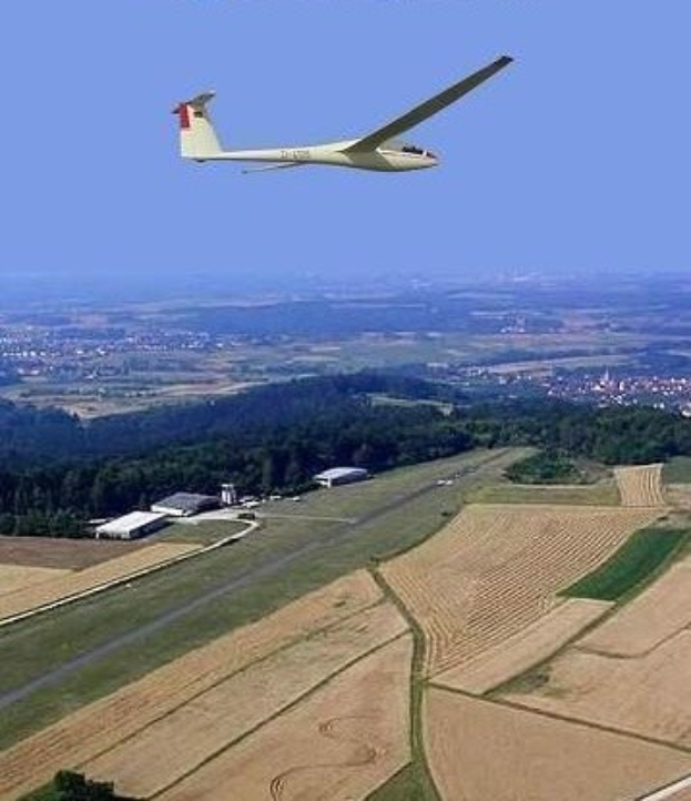 Ein Segelflugzeug, das über ein Feld mit Bäumen und Gebäuden im Hintergrund fliegt, mit Text oben auf dem Bild.